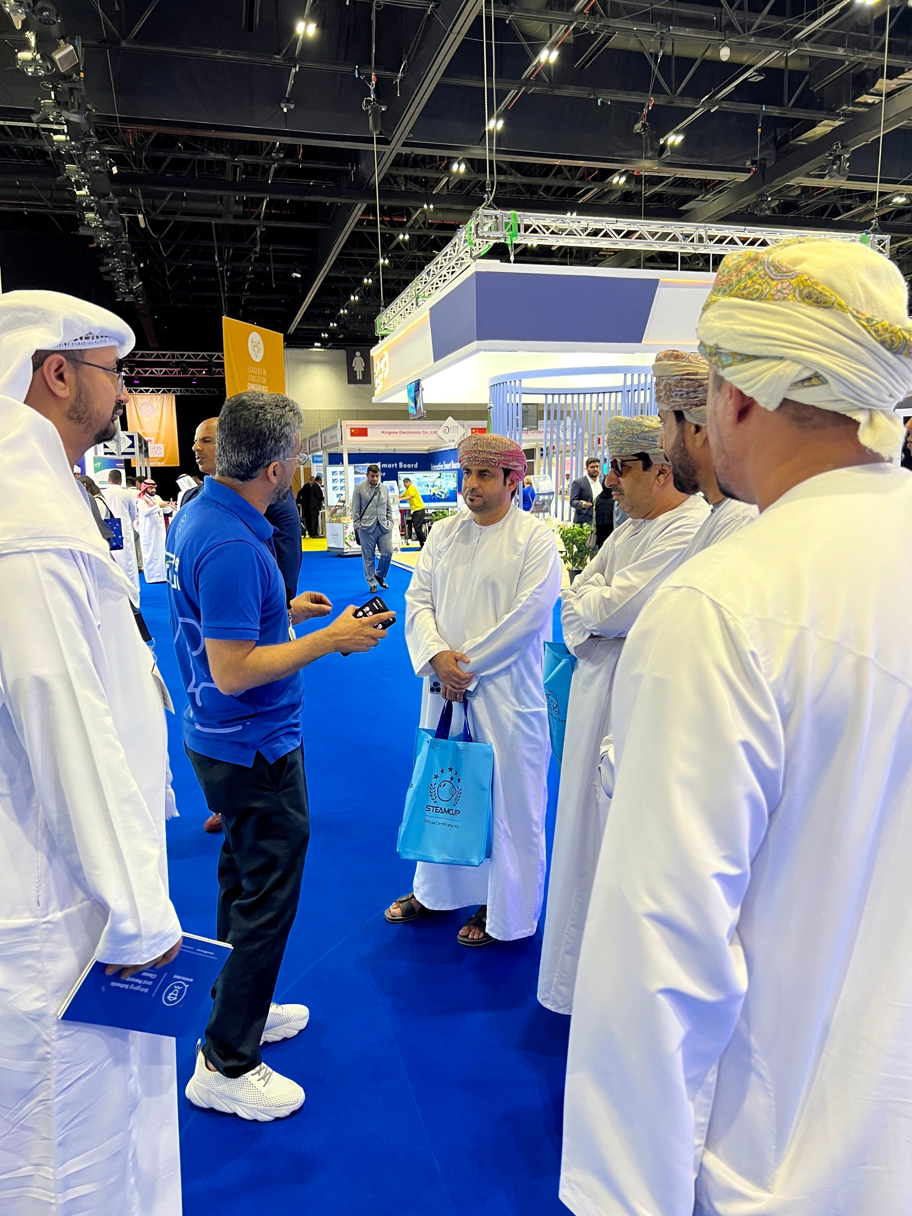 علي بن يحيى يناقش تأثير سكول فويس على تفاعل المدرسة مع أولياء الأمور مع مجموعة من التربويين العمانيين بالزي التقليدي خلال جيس دبي، مركزاً على التحول الرقمي في التواصل المدرسي