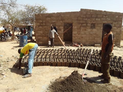 Image of community members building mud bricks