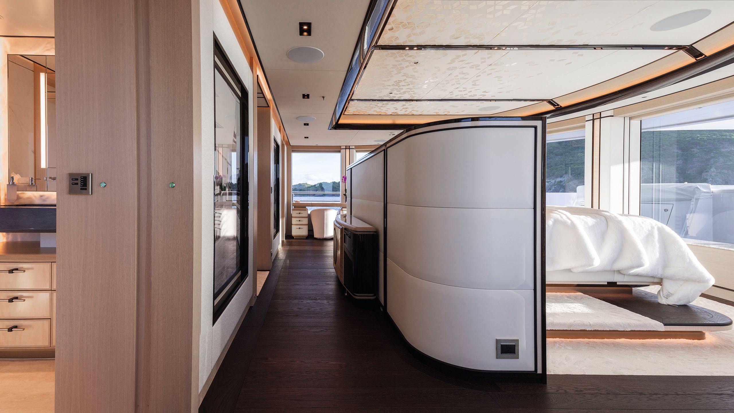 Looking down a bedroom cabin - the bed is to the right behind a partition looking out of huge windows. To the left is a bathroom area