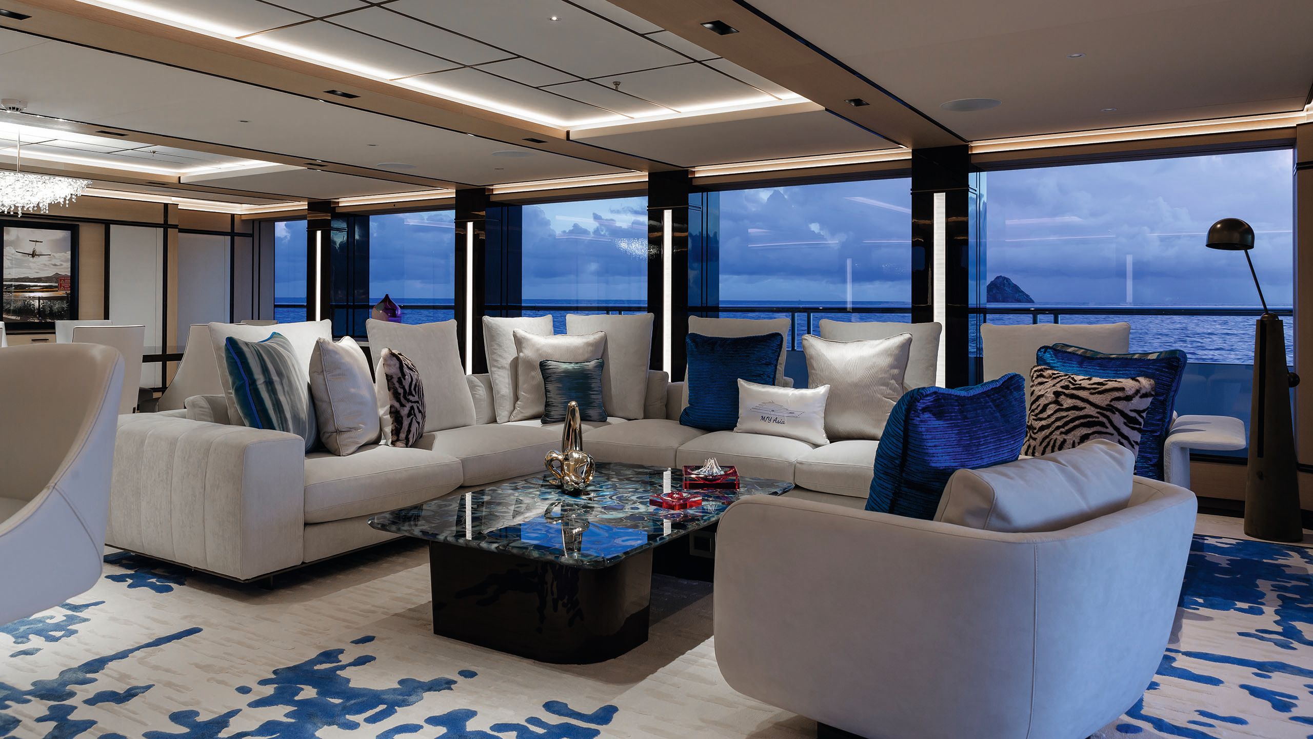 L-shaped neutral sofa with blue accent cushions and a white and blue rug with abstract print