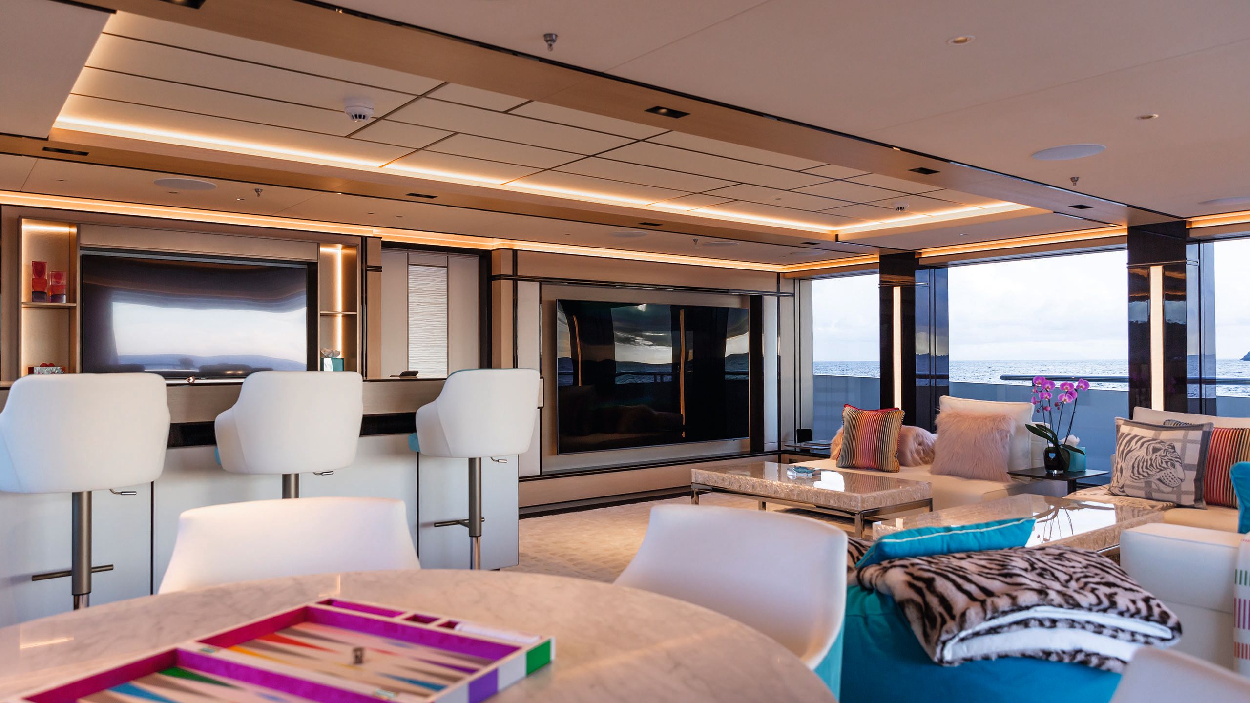 Countertop area with high stools, a round table with chairs and softer seating and a TV area in the background