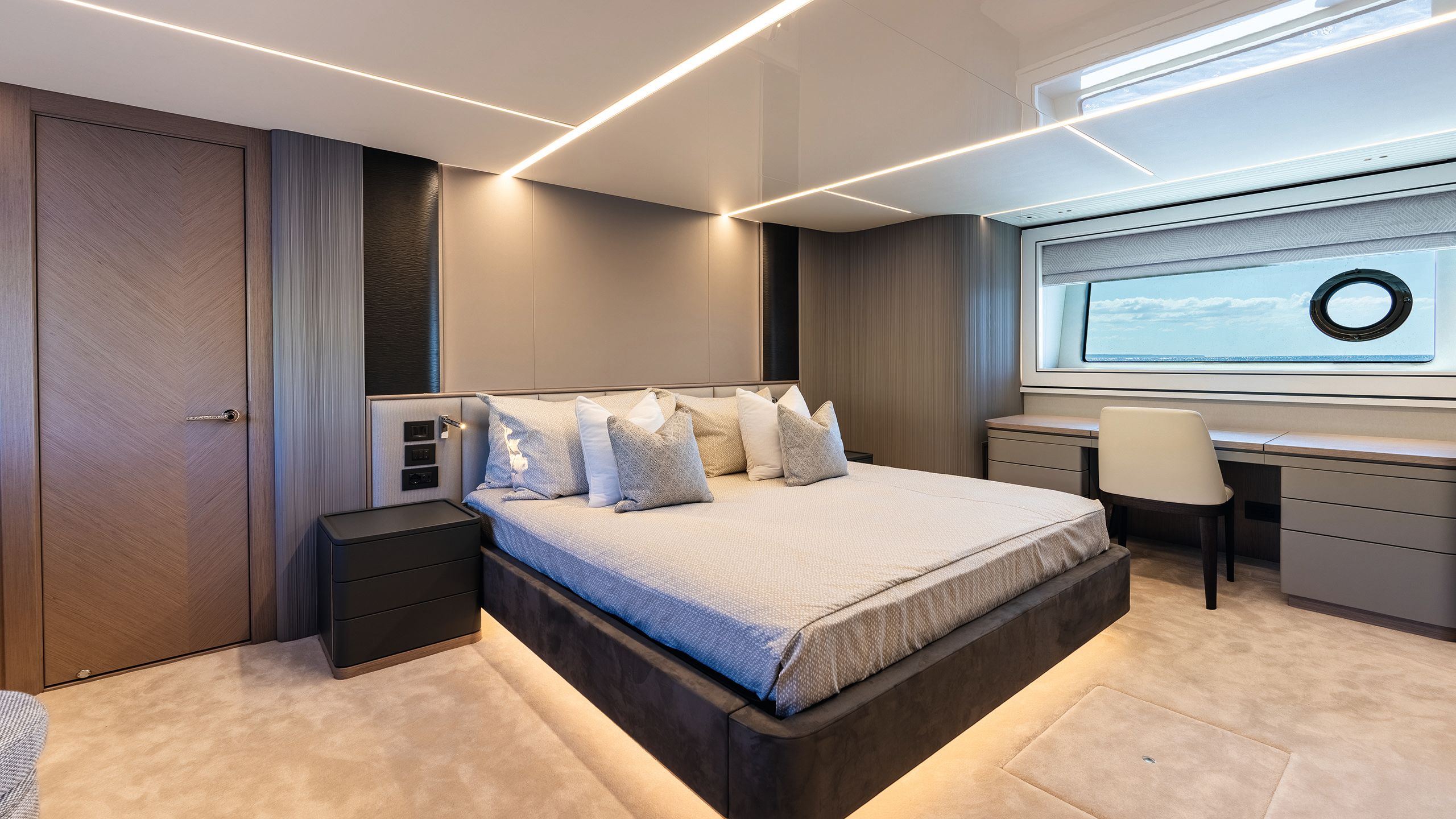 Bed on a raised under-lit plinth with bedding in brown, grey and neutral pallete