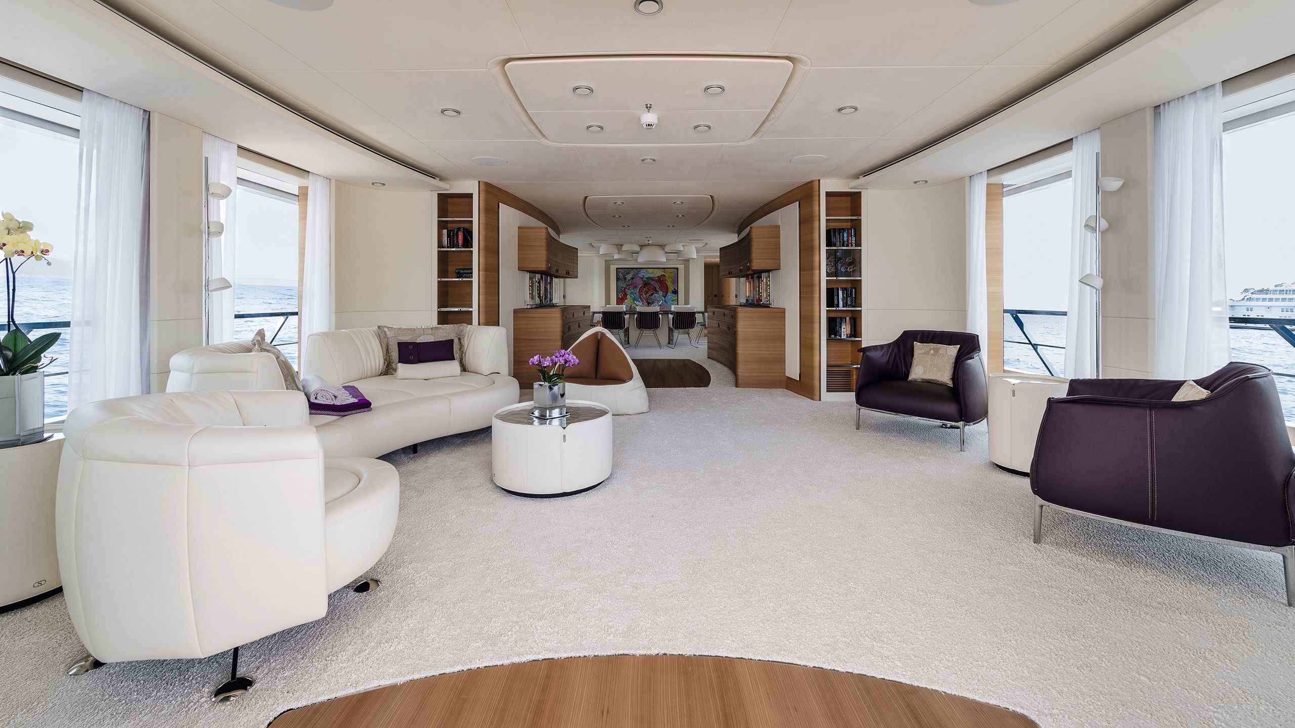 Lounge area with white leather sofa, arm chairs and table on white carpet