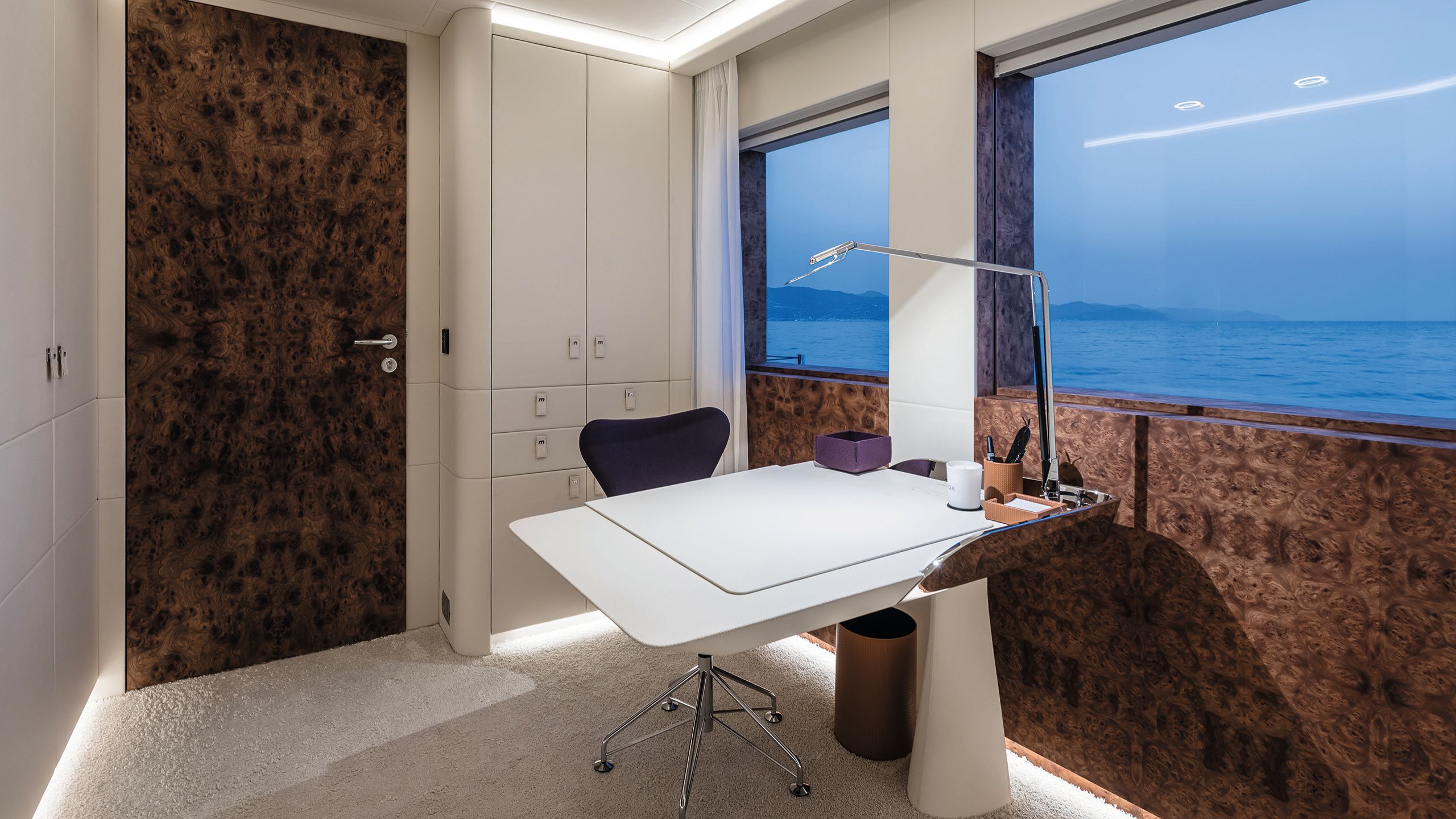 White desk with black chair and large window to side