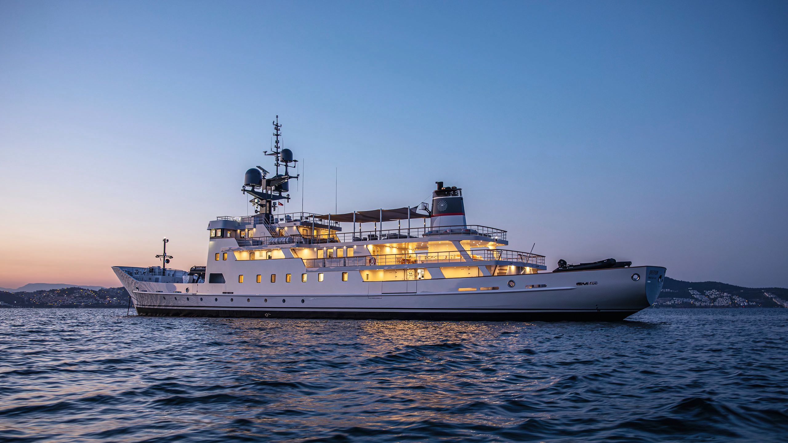 Jester on the water, shot from the side. The light is dusky and the decks are lit.