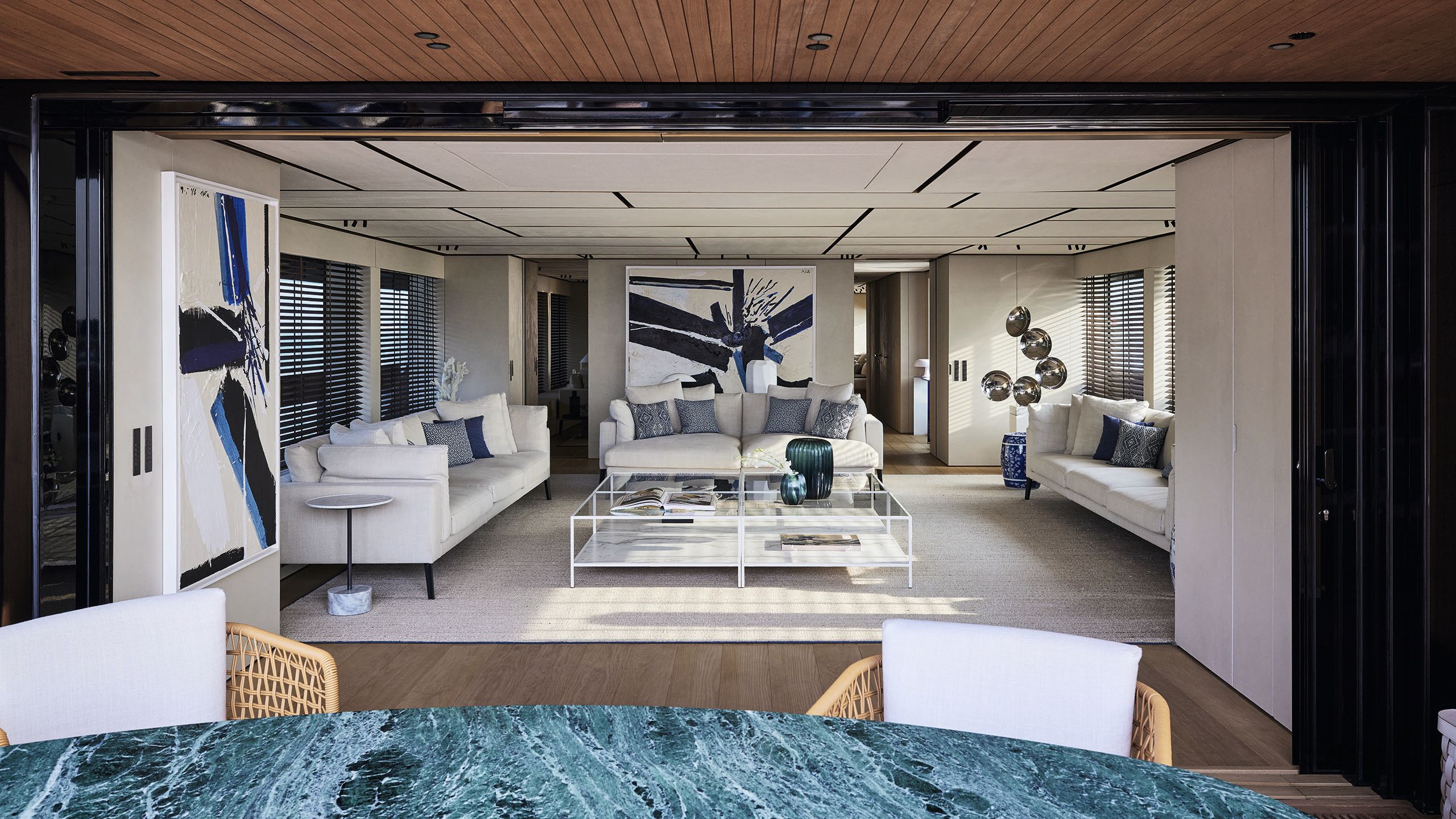View from the marble dining table looking into the lounge, which has three white sofas and a white and glass table in the centre on a white rug