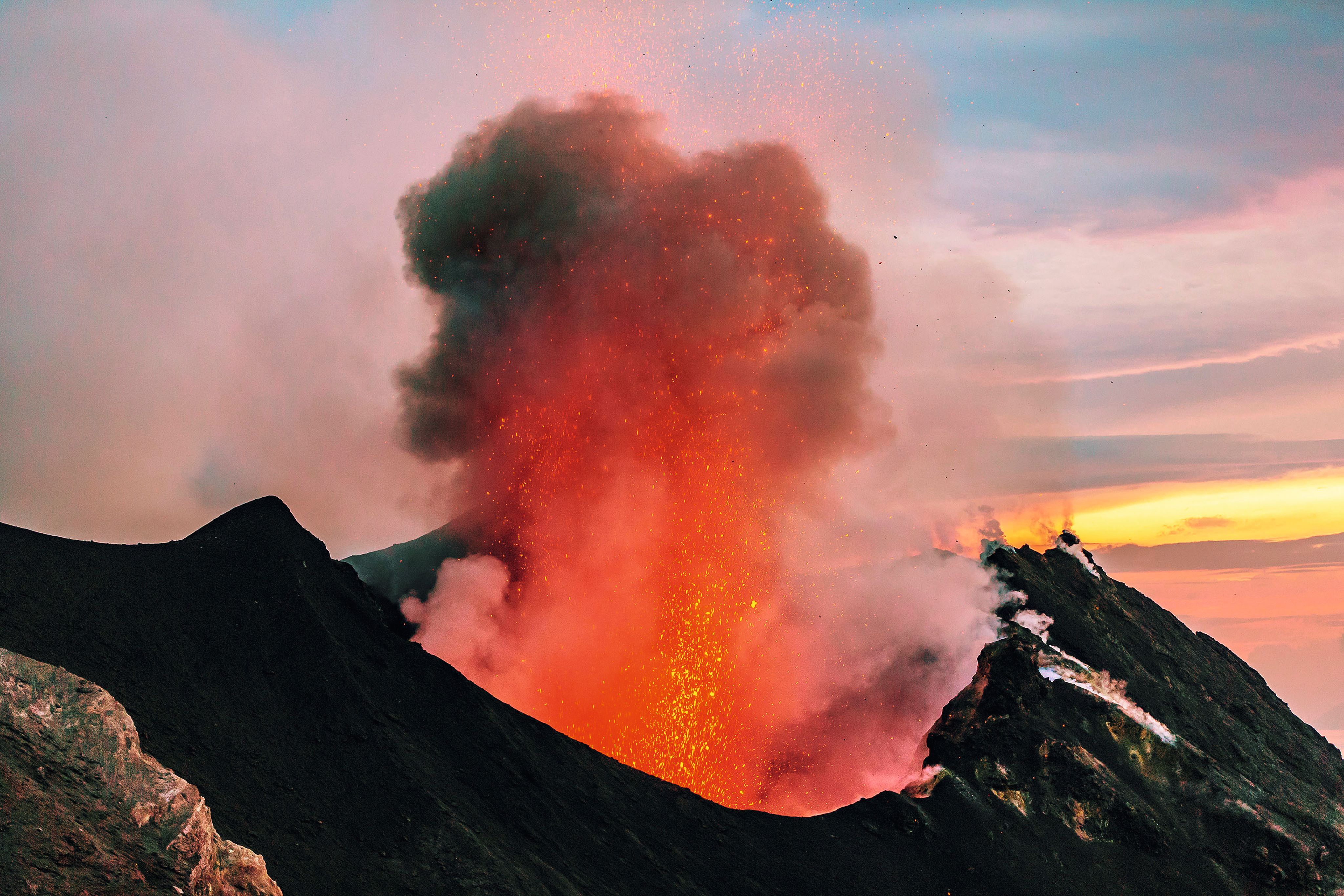 Lava erupting from a volcano, sending black smoke into the sky