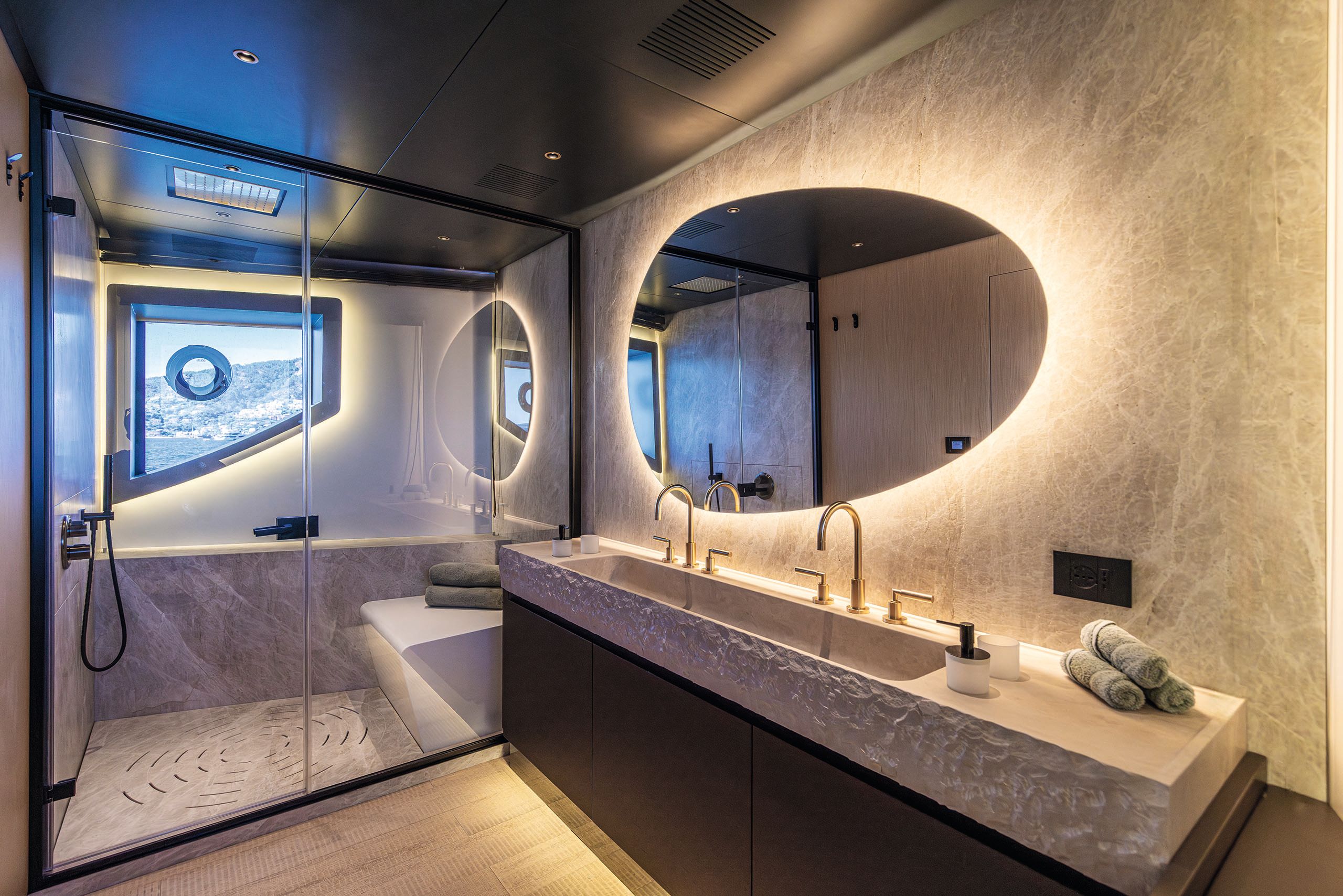 Bathroom showing lit mirror, vanity and walk-in shower