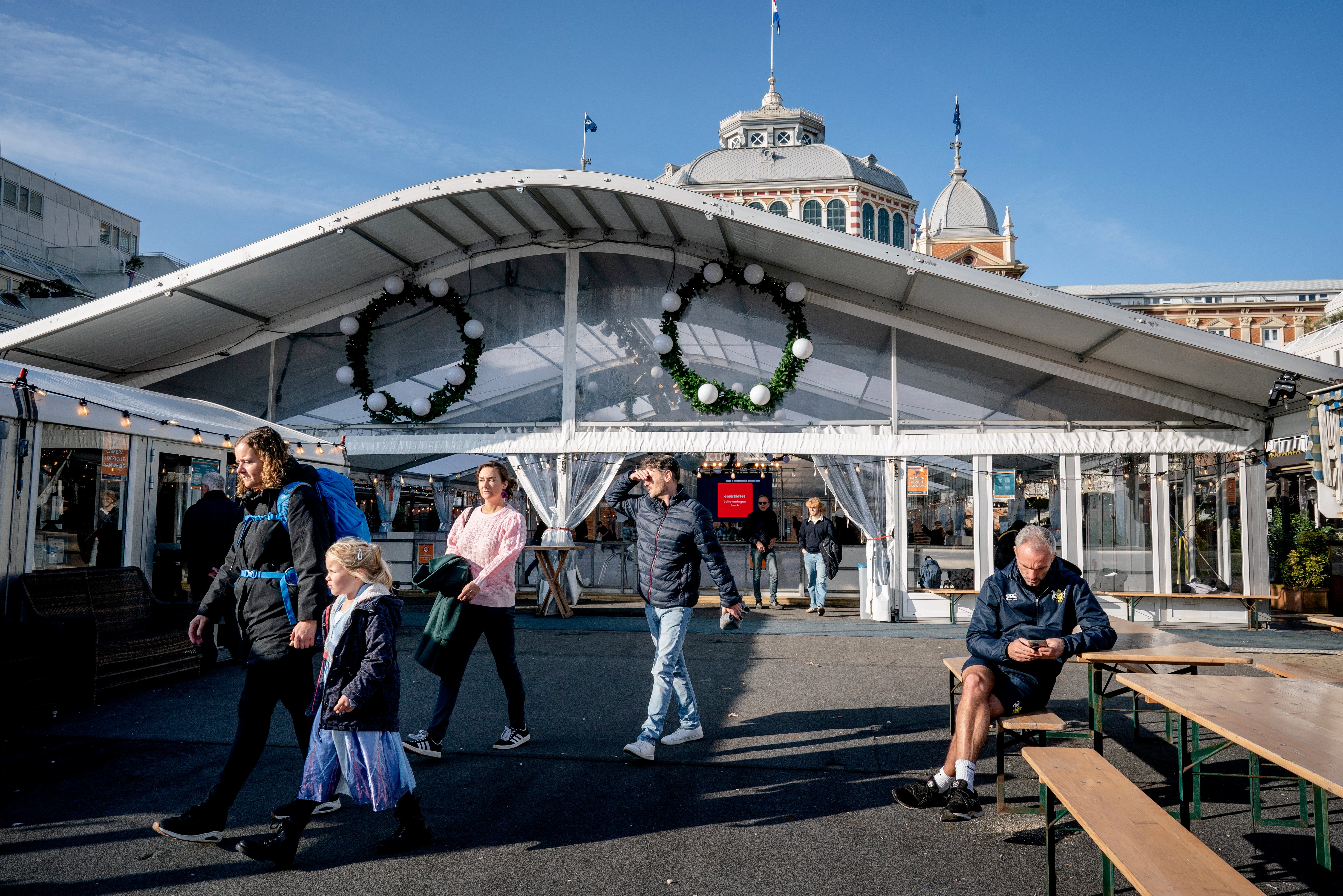 Los transeúntes disfrutan del clima cálido en la pista de hielo artificial, junto al Kurhaus en Scheveningen.