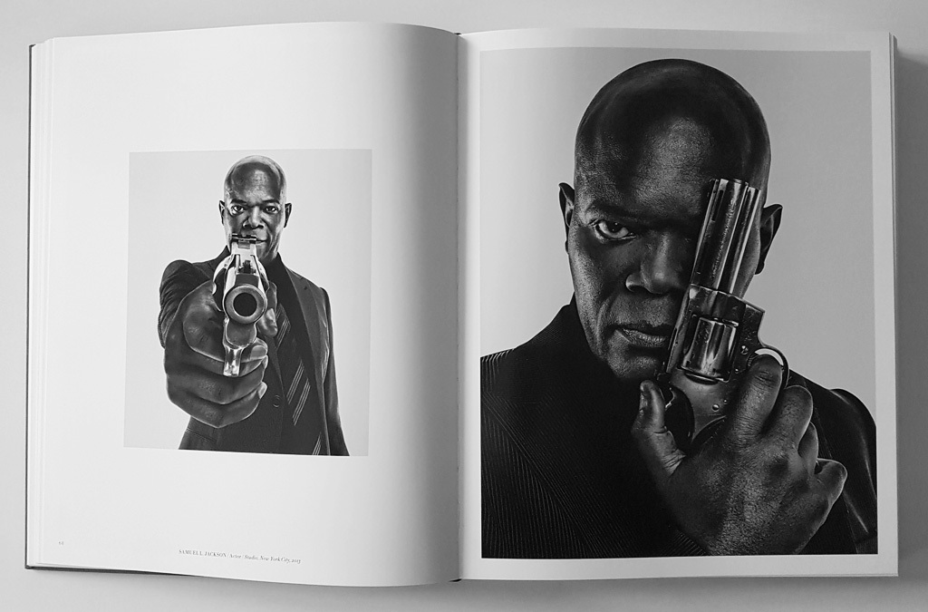 A monochrome photograph in a book depicting Samuel L. Jackson holding a revolver pointed directly at the camera, with an intense gaze, capturing a sense of drama and power.
