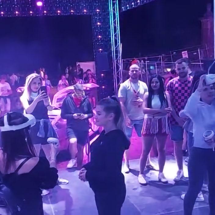 A dynamic scene at the EXIT Festival's VR Zone with festival-goers engaging in a lively party atmosphere. People are dancing and interacting with each other under purple-tinted lights, surrounded by stage equipment. This encapsulates the immersive experience created by Digital Mind, allowing participants to virtually step into the vibrant environment of the EXIT Festival as if they were present during the event itself.