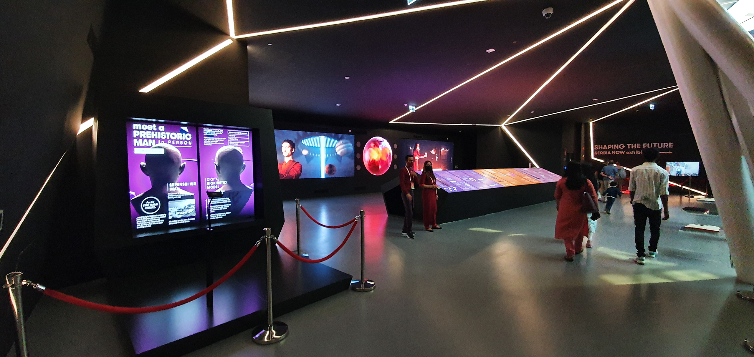 The interior of the Serbian Pavilion VR Zone, where visitors can view exhibitions on digital screens. The displays feature information about Serbian and international artists, and the space is enhanced by sleek, modern design elements and ambient lighting that guide visitors through the immersive VR journey.