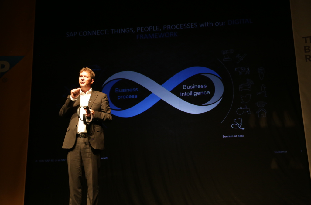 A presenter speaks at the 13th SAP Forum Belgrade 2017 about digital business trends with a visual aid highlighting business process and intelligence.