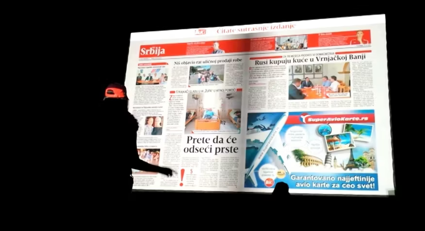 An individual flipping through a digital publication displayed on a large screen using Gesture Page Flipping technology, giving the impression of turning real paper pages in a public promotional event.