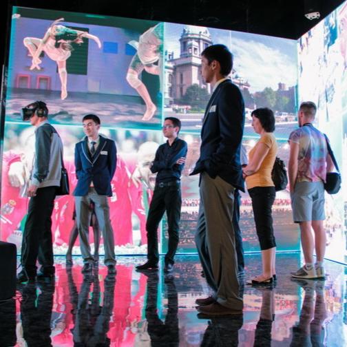 Visitors engage with an interactive display showcasing Serbia's athletic prowess at the World Expo Astana 2017, using IR motion sensors for immersive experiences.