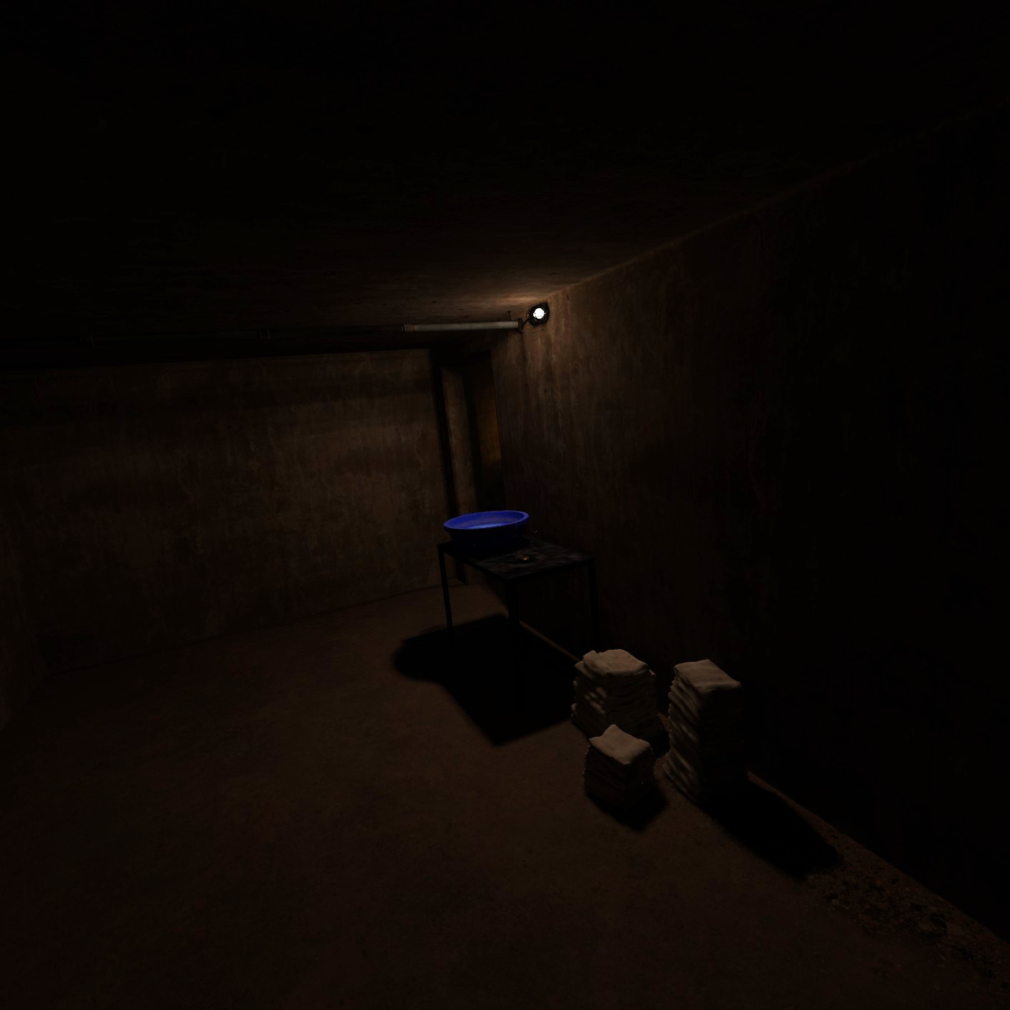 A blue basin sits on a table in a dimly lit room. Towels are stacked on the floor next to the table.