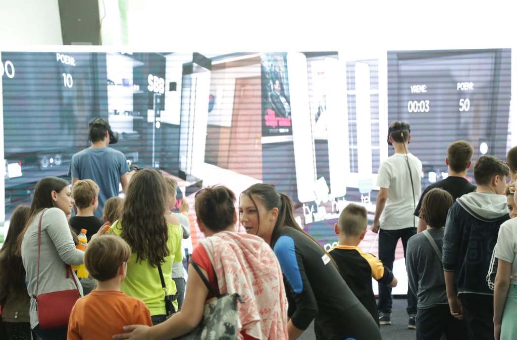 A group of children and adults gathered around a VR gaming area.
