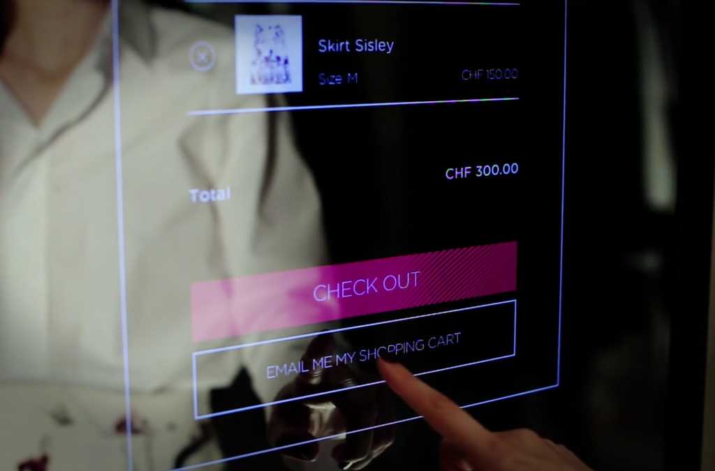 A close-up of a touch-sensitive virtual fitting room interface where a customer is about to email their shopping cart, illustrating the convenience of modern retail technology.