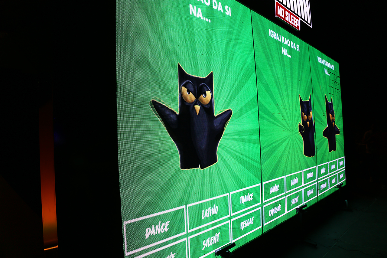 A large LED screen at the Guarana No Sleep stage at EXIT Festival displays an animated Guarana owl avatar with various music genres listed below, part of an interactive dance game where participants' movements are tracked and displayed in real-time.