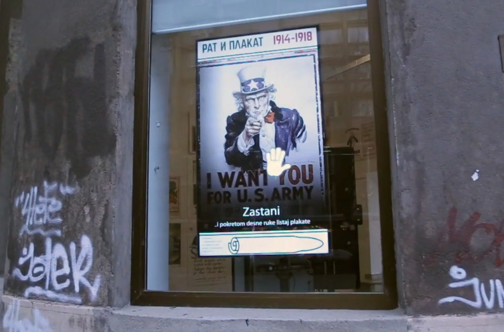 A passerby stops to view a vintage U.S. Army recruitment poster through an interactive display outside the Museum of Applied Art.