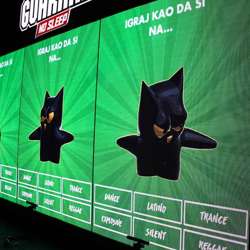 A large LED screen at the Guarana No Sleep stage at EXIT Festival displays an animated Guarana owl avatar with various music genres listed below, part of an interactive dance game where participants' movements are tracked and displayed in real-time.