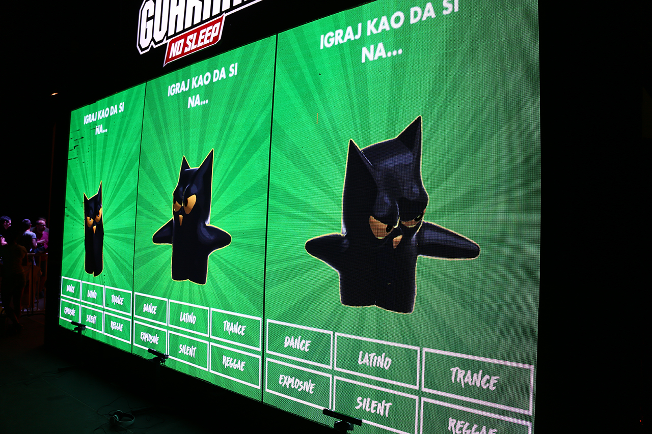 A large LED screen at the Guarana No Sleep stage at EXIT Festival displays an animated Guarana owl avatar with various music genres listed below, part of an interactive dance game where participants' movements are tracked and displayed in real-time.