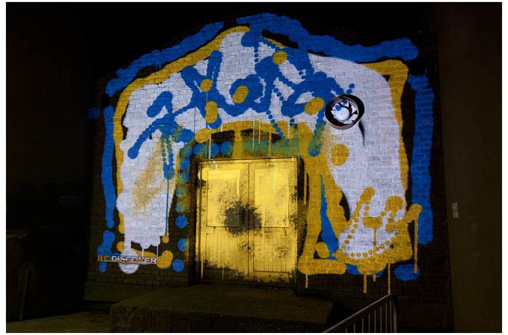 A colorful projection mapping abstract patterns on a building's facade, creating a vivid 3D effect around a rustic doorway.