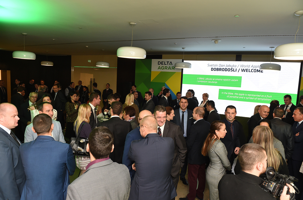 A crowded event space with attendees mingling and exploring exhibits, the room features banners and displays for an interactive learning experience about agricultural products.