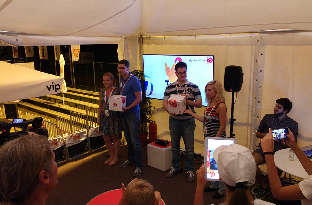 A group of participants celebrate a victory at a VIP Mobile Kinect volleyball game station, with one holding a prize.