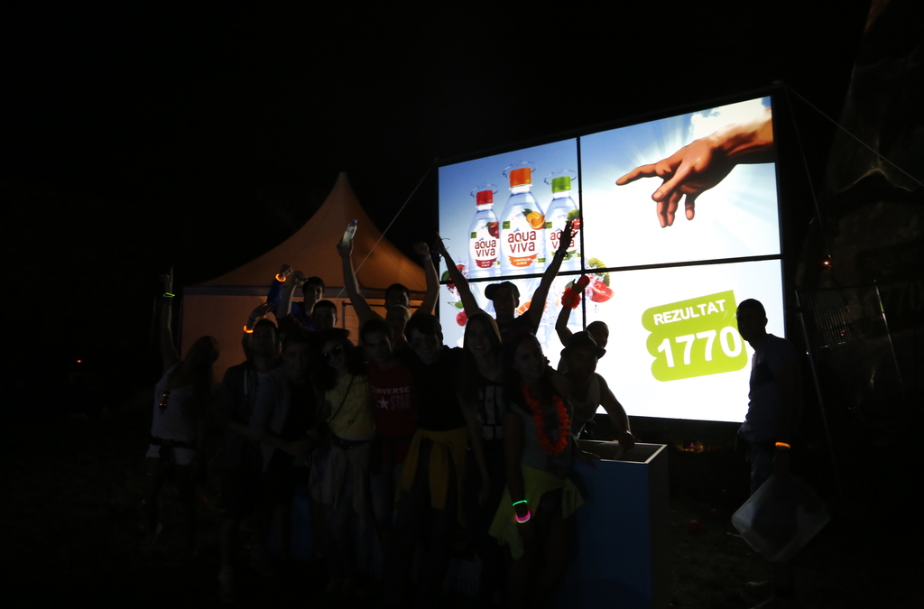 A group of festival-goers engages in a ball throwing game on a large multi-touch screen at the EXIT festival, part of an Aqua Viva brand activation.