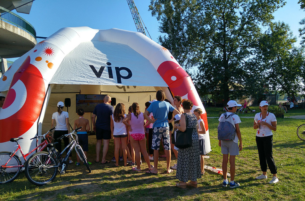 Visitors queue outside a VIP Mobile tent to experience the Kinect volleyball installation at a beach volleyball event.