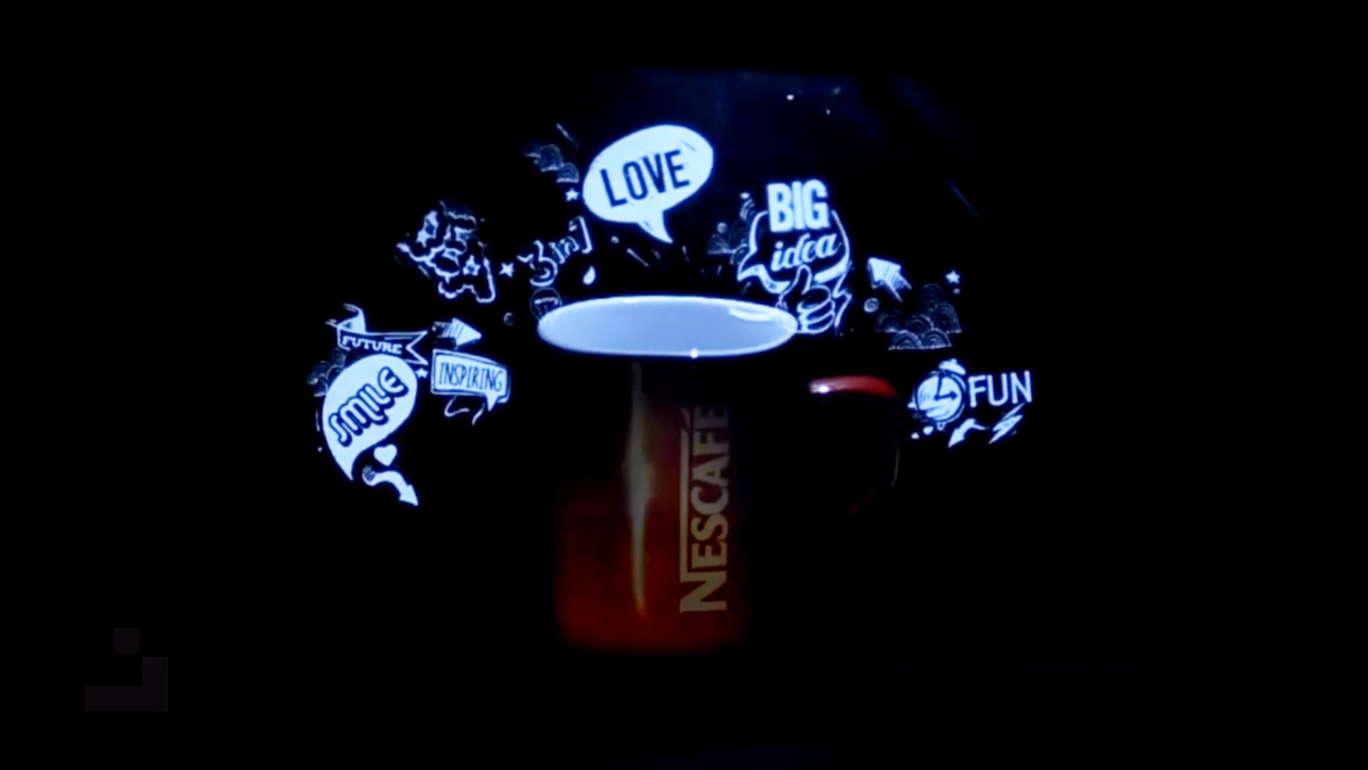 A Nescafe cup placed within a hologram pyramid, with animated words like "LOVE," "BIG IDEA," "SMILE," and "FUN" floating above it against a dark background, showcasing a blend of physical and digital display.