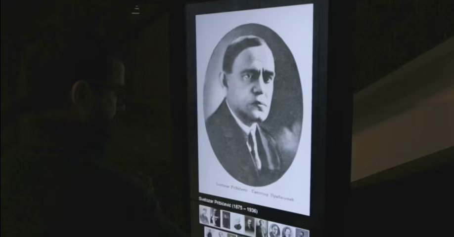 A museum-goer using an interactive totem to view a historical portrait of Svetozar Pribićević among other significant figures at the Museum of Yugoslav History.