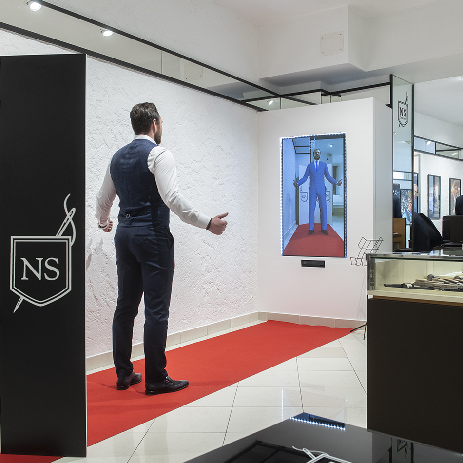 A man interacts with NS Concept's Virtual Mirror in a clothing store, virtually trying on a suit.