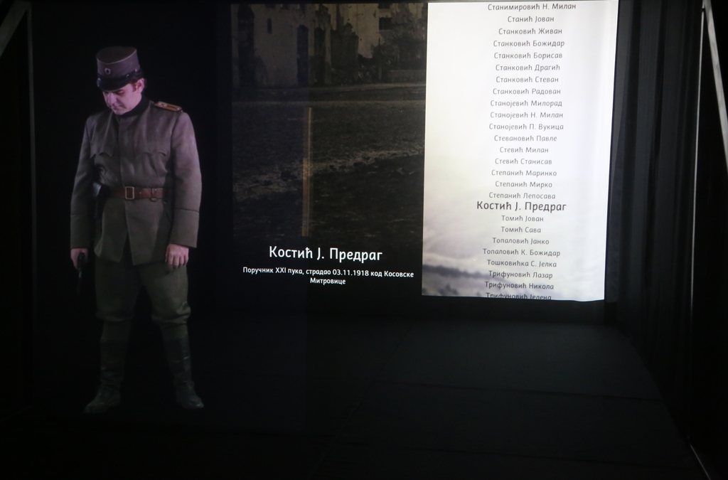 A hologram of a male WWI soldier in uniform is displayed in front of a backdrop with a list of names from the era.