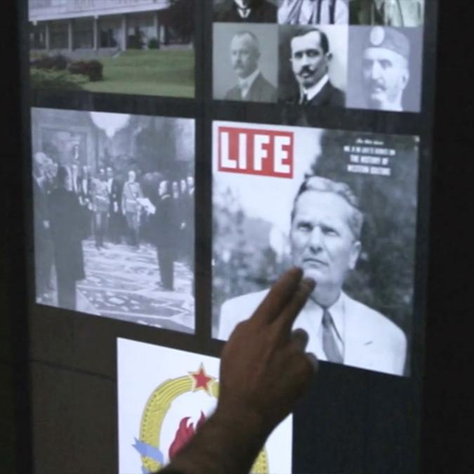 A hand points to an interactive digital display featuring historical photos and a 'LIFE' magazine cover, part of an exhibit at the Museum of Yugoslav History.