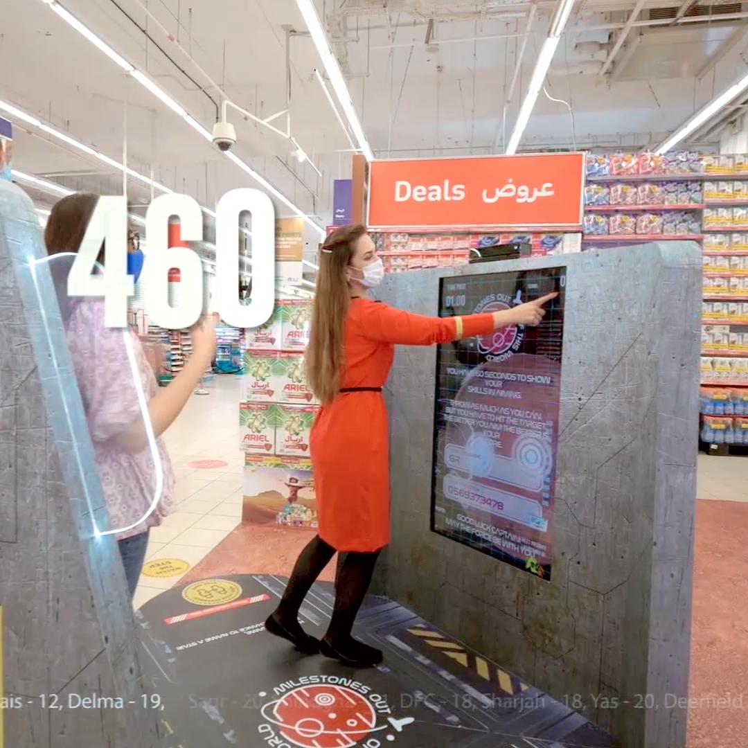 Interactive gaming kiosk in a supermarket setting, featuring the "MARS Landing Kinect Game" by Digital Mind.he kiosk showcases an on-screen display with Procter & Gamble (P&G) branding and a countdown timer, promoting engagement by combining retail with the celebration of the UAE's first Mars mission.