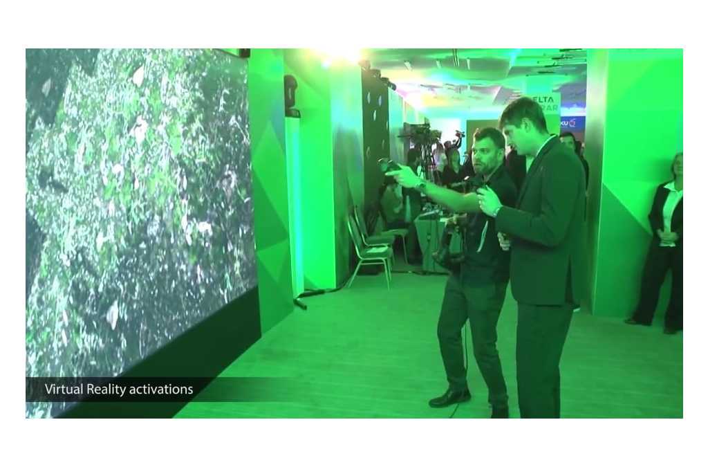 Two people wearing virtual reality headsets engage with a VR demonstration in a room bathed in green light, indicative of a high-tech, interactive learning experience about agricultural products.