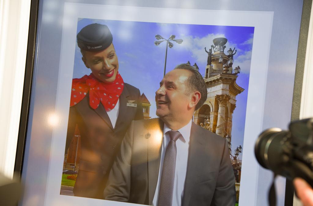 A man smiles as he poses next to a life-sized print of an Air Serbia flight attendant.
