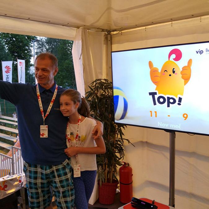 An adult and a child celebrate their score in a Kinect volleyball game at a beach volleyball event sponsored by VIP Mobile.