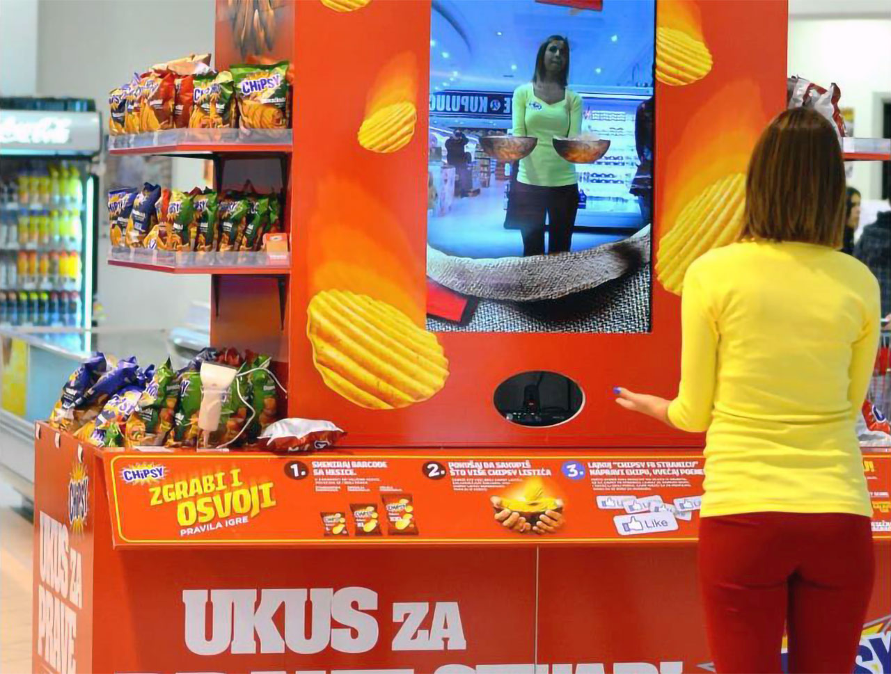 A woman playing the Chipsy AR game, focused on catching falling virtual potato chips on the screen, in a supermarket promotion area.