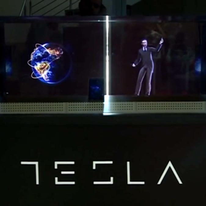 A display case with the Tesla logo illuminates a holographic projection of Nikola Tesla. The exhibit is designed to promote the new Tesla smartphone, symbolizing the fusion of technology and Tesla's scientific legacy.