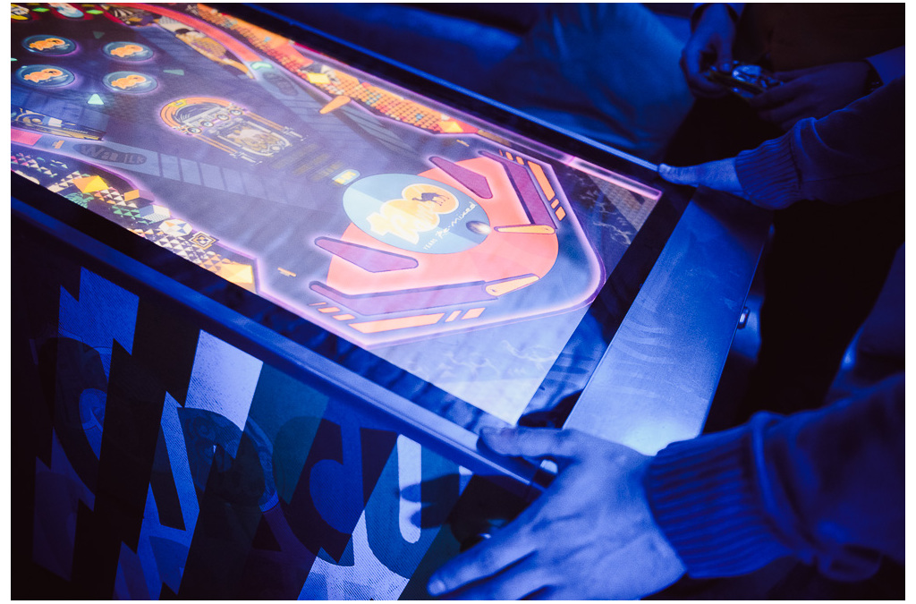 A player engages with a digital pinball machine featuring a Camel brand theme, illuminated in blue.