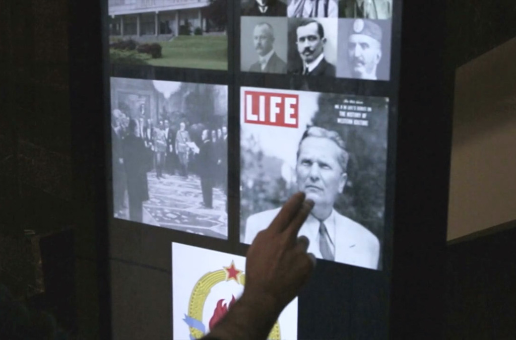A hand points to an interactive digital display featuring historical photos and a 'LIFE' magazine cover, part of an exhibit at the Museum of Yugoslav History.