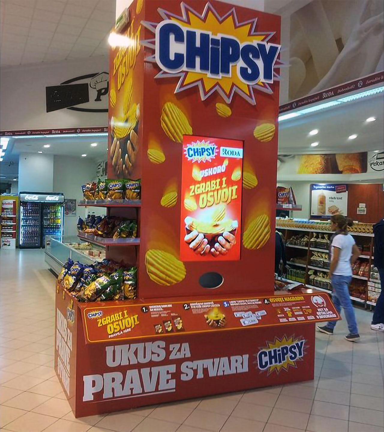 A promotional Chipsy kiosk with an augmented reality game screen in a supermarket, inviting customers to play a chip-catching game.