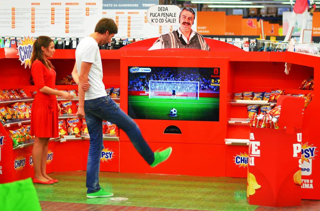 A customer takes a penalty kick at an in-store interactive soccer game display.