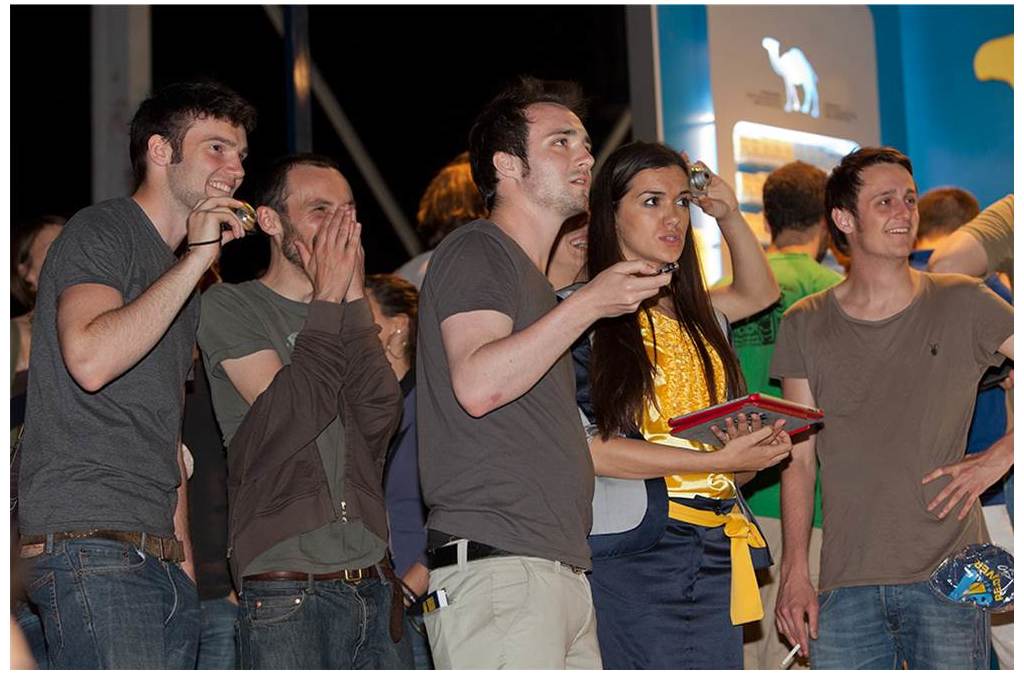 A group of onlookers express surprise and delight, watching a laser painting demonstration.