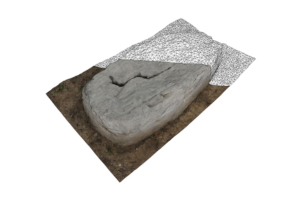 Realistically textured 3D model of a flat ancient tombstone with cracks, surrounded by grass and partially covered by a wireframe overlay.