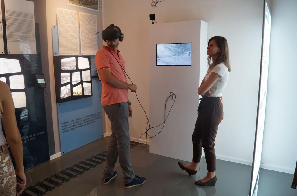 A person wearing a VR headset facing a screen showing a snowy scene.