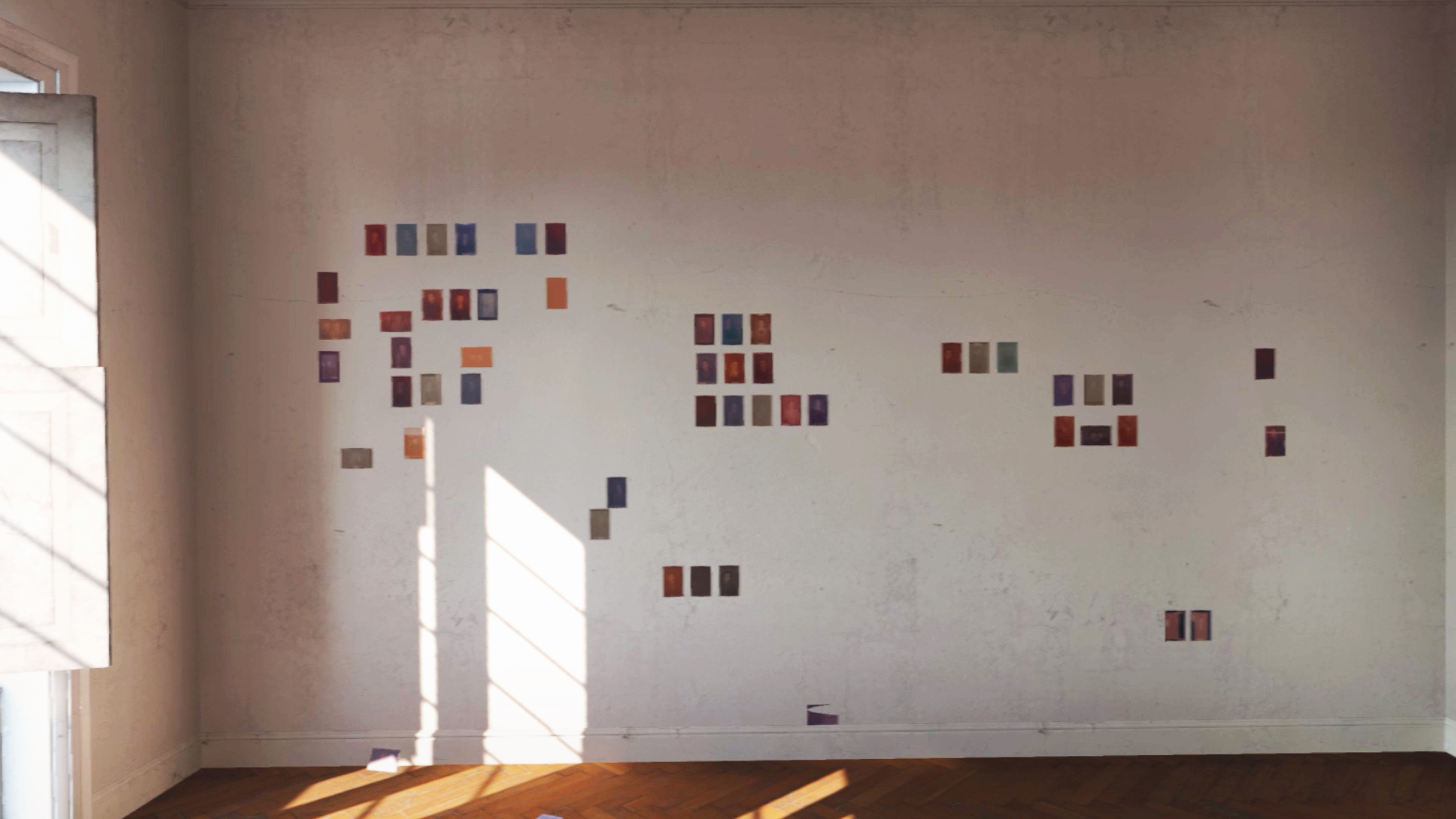 A close-up view inside a bright room with a herringbone parquet floor, where small, framed photographs are arranged in a seemingly random pattern on a sunlit wall, part of Mia Cuk's virtual exhibition.